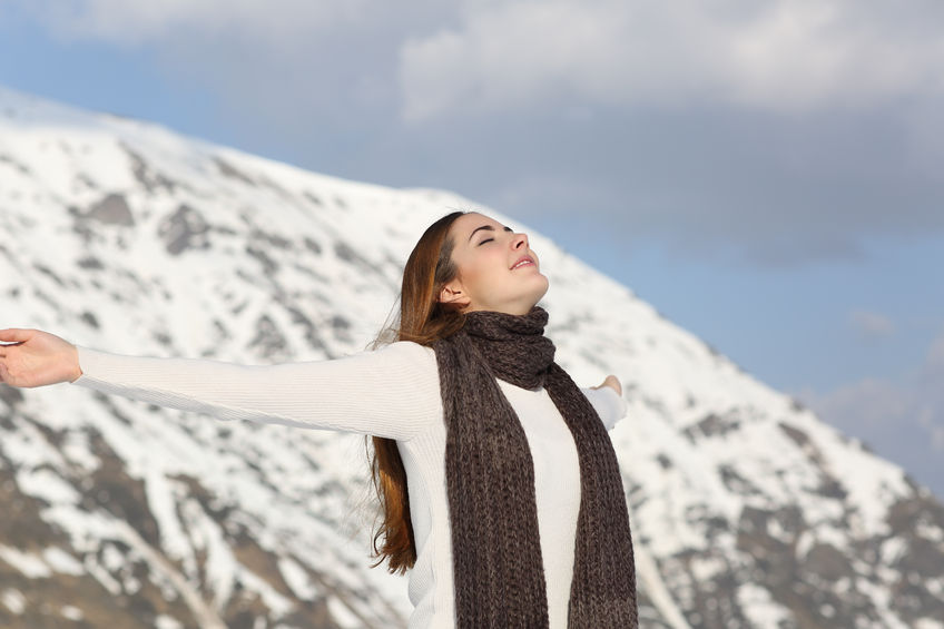 34326655 - woman breathing fresh air raising arms in winter with a snowy mountain in the background
