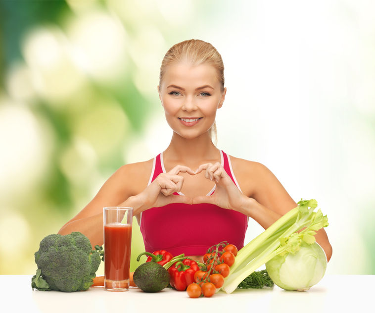 26175792 - fitness, diet and food concept - smiling woman with organic food showing heart shape with hands