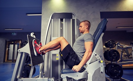 60804631 - sport, fitness, bodybuilding, lifestyle and people concept - man exercising and flexing leg muscles on gym machine